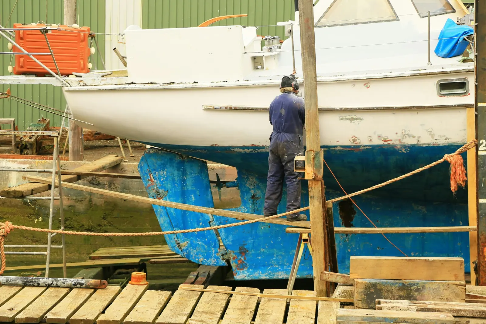 Boatyard worker maintaining the hull of a sailing boat